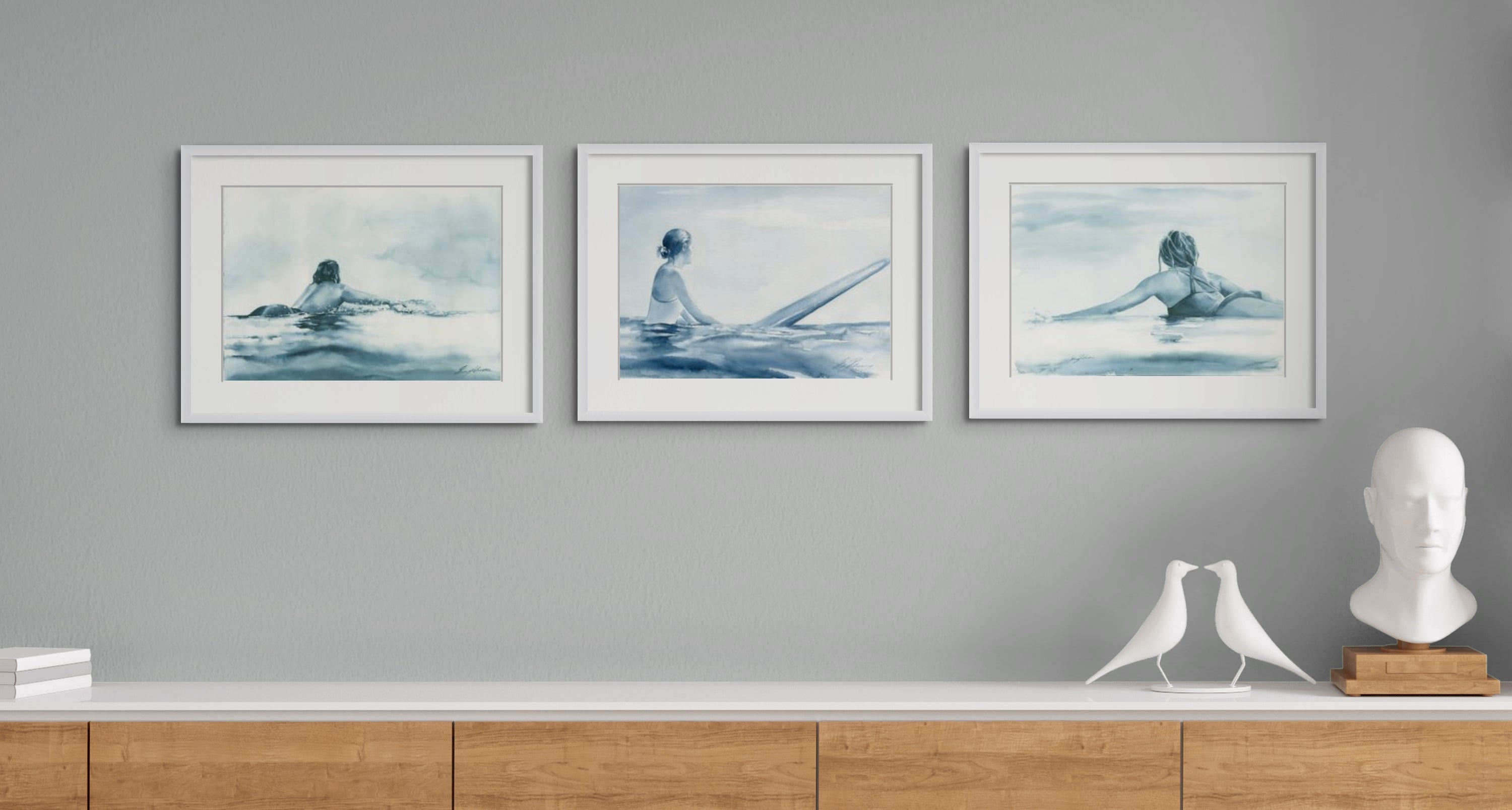 Three coastal art watercolour paintings of surfers on surfboards in calm ocean waters.