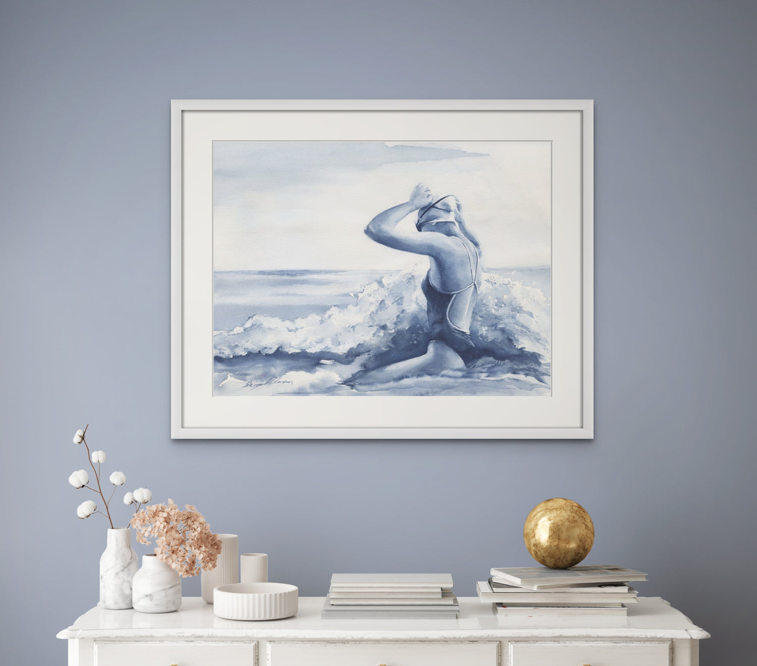 A coastal wall art watercolour painting of an ocean swimmer entering the surf. She heads into the blue as the wave surrounds her.